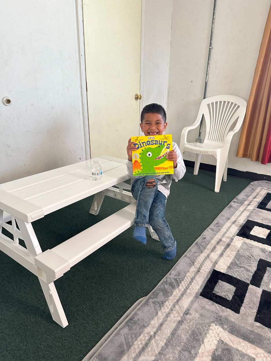 Child Posing with book, Marshallese Mini-Library Project (BC/CLC Sponsored Project)